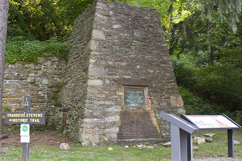 A stone structure with a plaque set into its base and an informational sign in front