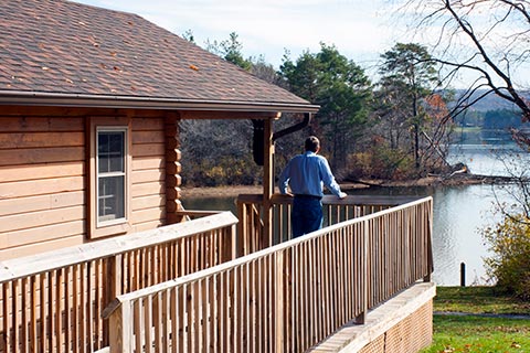 A man enjoys a view of the lake from the porch of a log cabin at Yellow Creek State Park.