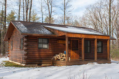 A modern log cabin in in snow at Black Moshannon State Park.