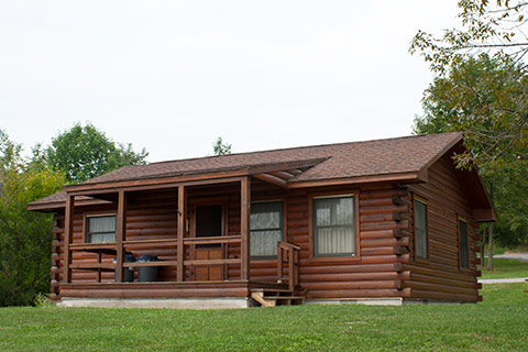 A modern log cabin is near trees at Canoe Creek State Park.