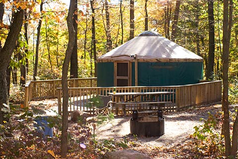 A round tent with a wooden floor is in the forest at French Creek State Park.
