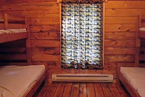Bunk beds, electric heat, and a window are part of the interior of a deluxe camping cottage at Hickory Run State Park.