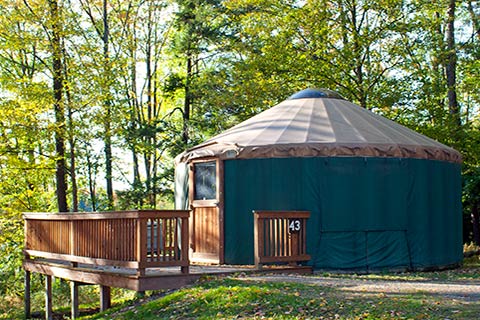 A round, canvas tent with a wooden proch is near trees at Hills Creek State Park.