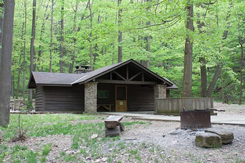 A modern, wainy-wood cabin is near trees at Linn Run State Park.