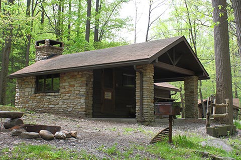A rustic, stone cabin is surrounded by trees at Linn Run State Park.