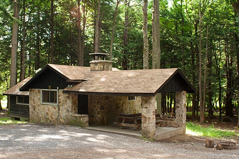A stone, rustc cabin is in the forest at Parker Dam State Park.