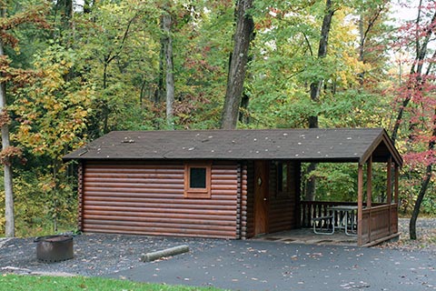 A cozy log cabin is near trees at Poe Valley State Park.