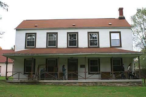 People enjoy a porch on a large, historic building at Trough Creek State Park.
