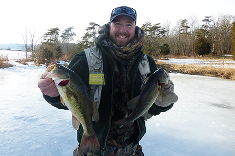 Ice angler holds his catch, two bass.