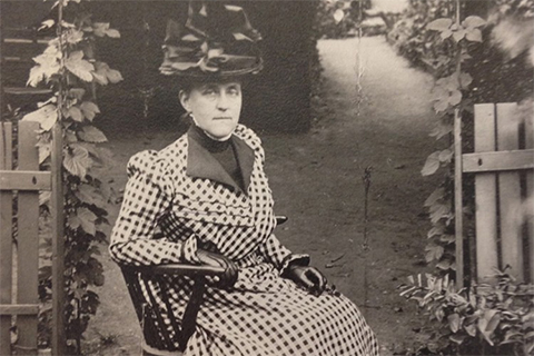 Woman sitting in a chair in early 1900's dress.