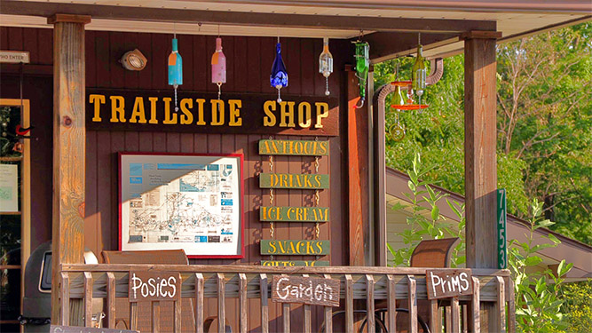 A store front with decorated bottles hanging outside and a sign that says: Trailside Shop