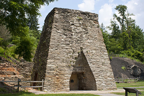 A tall, stone structure outdoors with a triangular opening at the base.